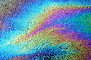 Rainbow oil slick from gasoline leak on wet pavement 